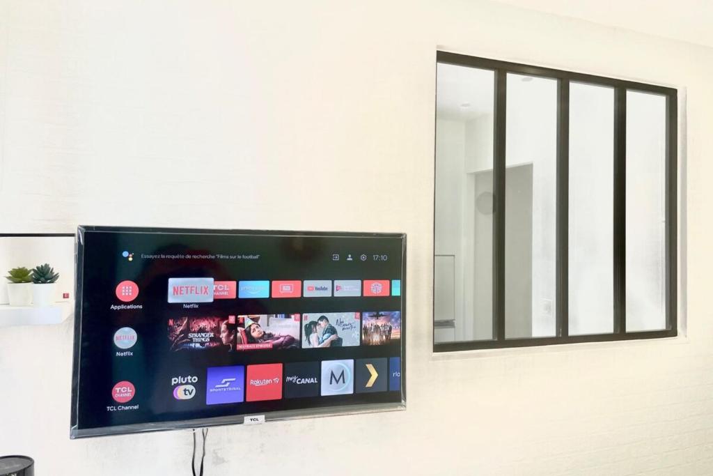 einen Flachbild-TV an einer Wand mit einem Fenster in der Unterkunft Chic And Cosy Studio proche ParisAéroport CDG in Villepinte