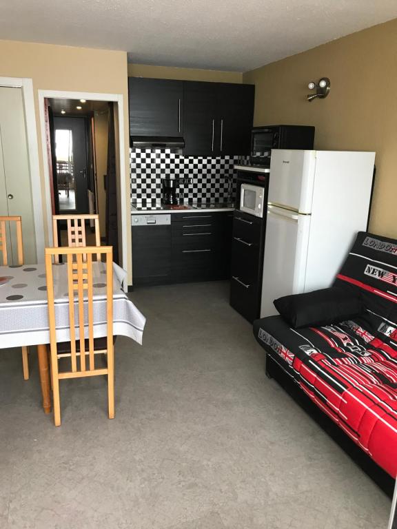 a kitchen with black cabinets and a white refrigerator at Mes vacances à Piau engaly in Aragnouet