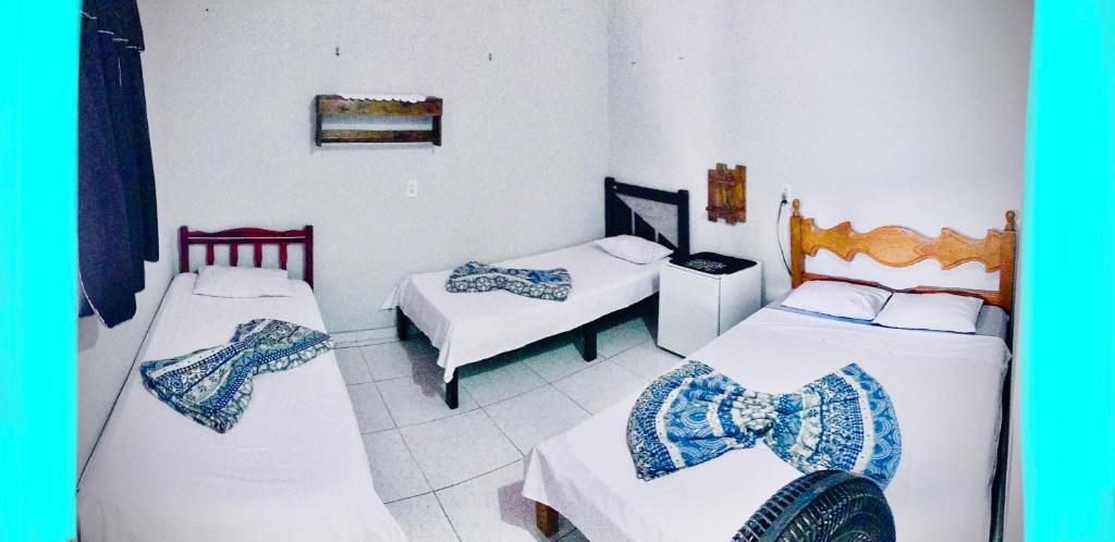 a room with two beds and a room with two tables at Pousada Rita Brandão in Jijoca de Jericoacoara