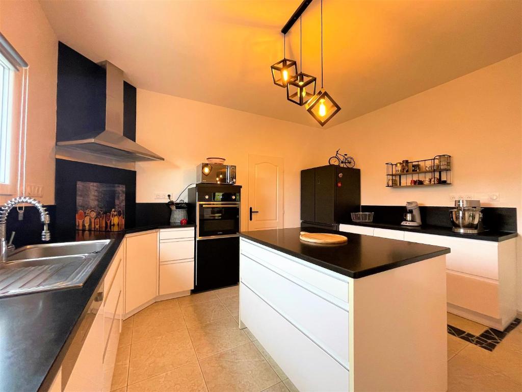 a kitchen with white cabinets and a black refrigerator at Villa au calme tout confort in Lapalud