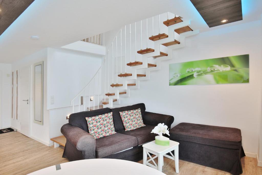 a living room with a couch and a staircase at Haus Miramar TREF Appartement 64 in Niendorf