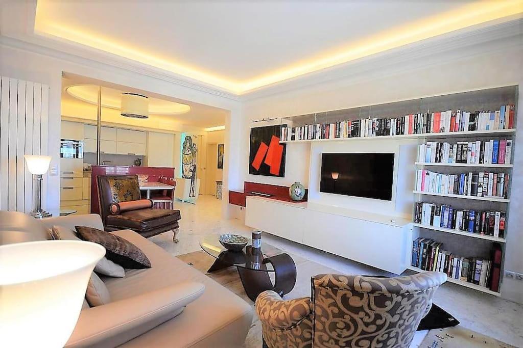 een woonkamer met een bank en een flatscreen-tv bij Palais Miramar Suite Art Modern - Derniere étages Vue Mer - 75m de confort - En Face des Plages -WIFI - Clim in Cannes