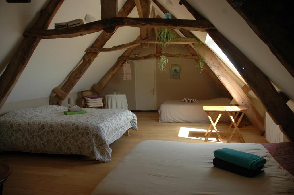 a attic bedroom with two beds and a table at Chambre d'Hôte La Maison du Mesnil in Saint-Hilaire-Petitville