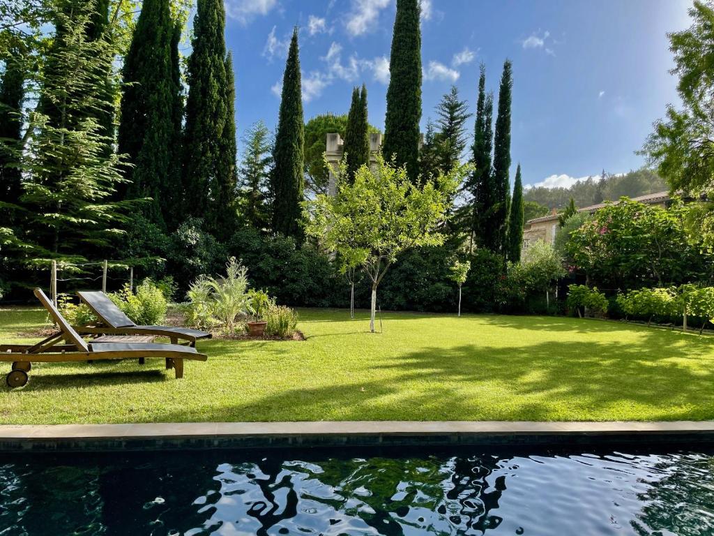 a garden with a bench and a pool of water at La Maison Du Village in Val-de-Dagne
