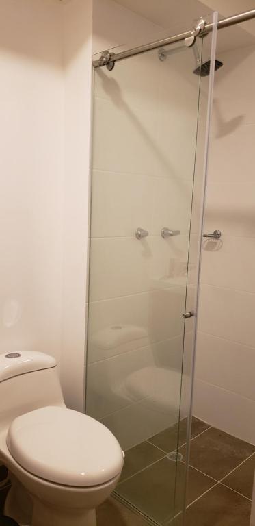 a bathroom with a toilet and a glass shower at Robles12 El Cable Luxury Highrise in Manizales