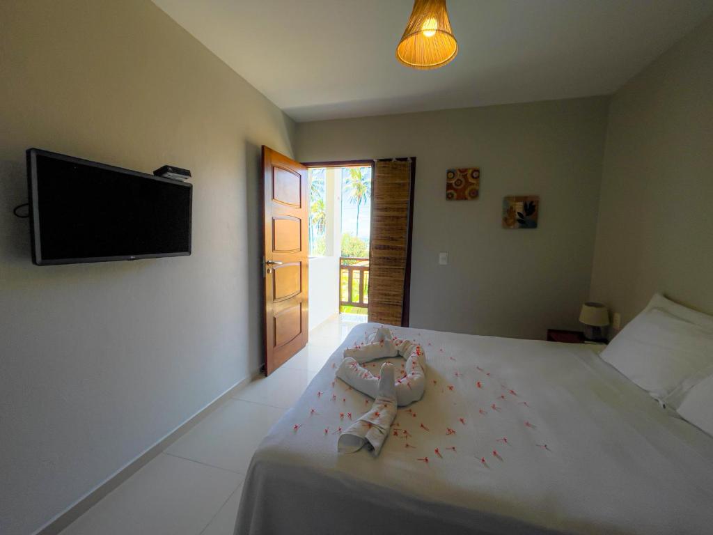 a bedroom with a bed with a flat screen tv at Pousada San Giovanni in Japaratinga
