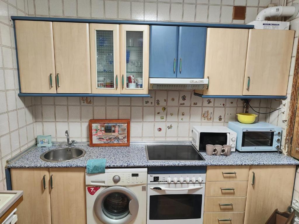 uma pequena cozinha com um lavatório e um micro-ondas em LAS LETRONAS em Gijón