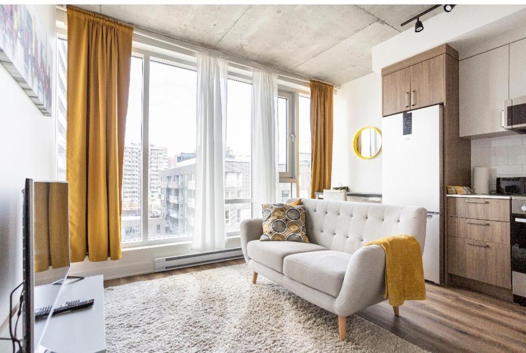 a living room with a couch and large windows at The Catherinoise, Condo in heart of downtown in Montreal