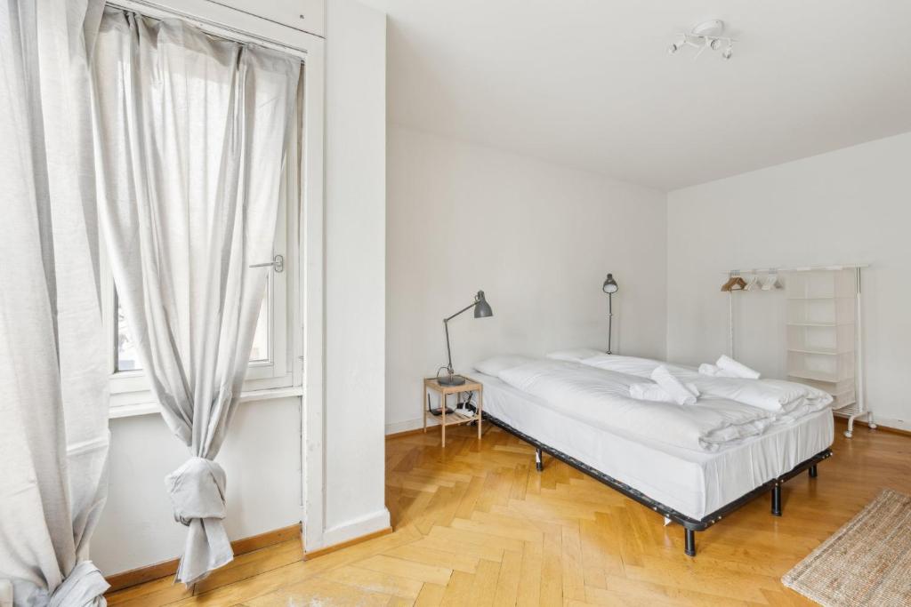 a white bedroom with a bed and a window at Central Apartment for City Explorers 224 in Zurich