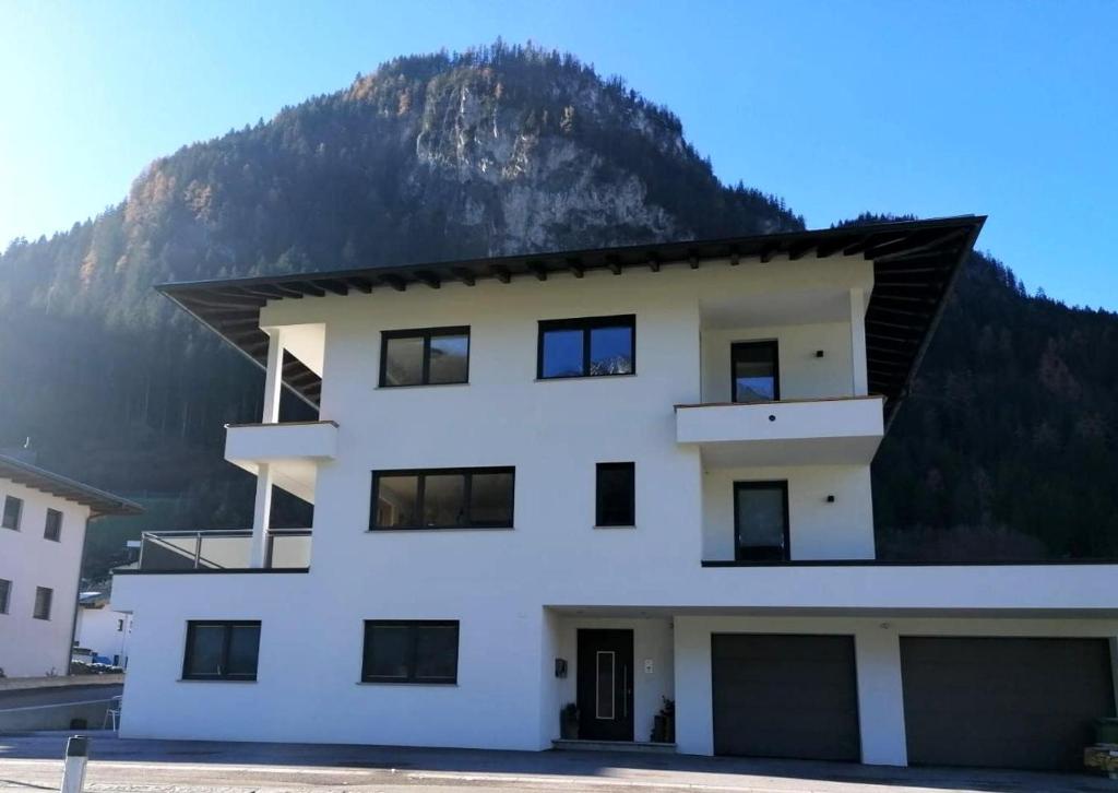 a white building with a mountain in the background at Apartment Filzenkogel in Schwendau