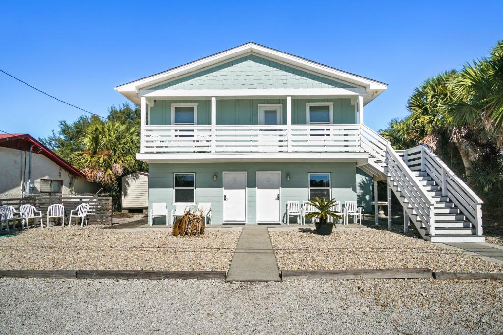 a house with white doors and chairs on a gravel driveway at Adorable Beach Cottages by Panhandle Getaways in Gulf Resort Beach