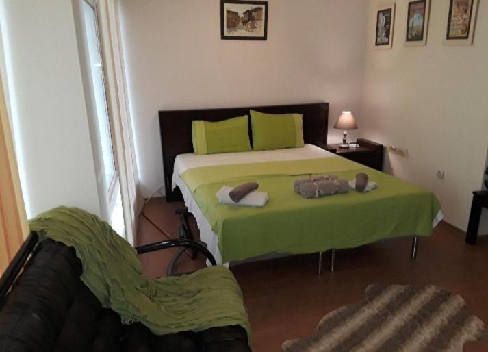 a bedroom with a bed with green sheets and a chair at Cozy apartment in the hart of the city in Varna City
