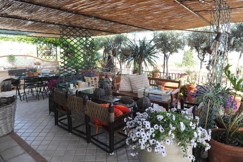 un patio con tavoli, sedie e fiori di Terrazza Pavone ad Aci Castello