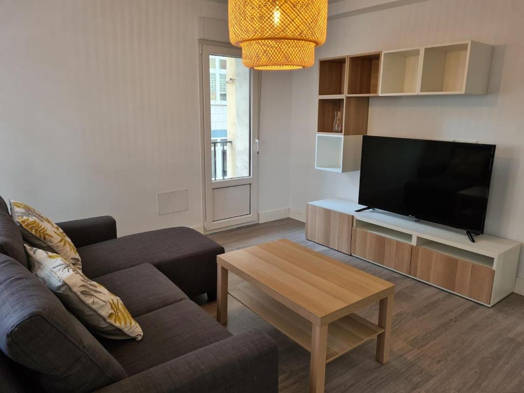 een woonkamer met een bank en een flatscreen-tv bij 124A Apartamento moderno 3 habitaciones in Gijón