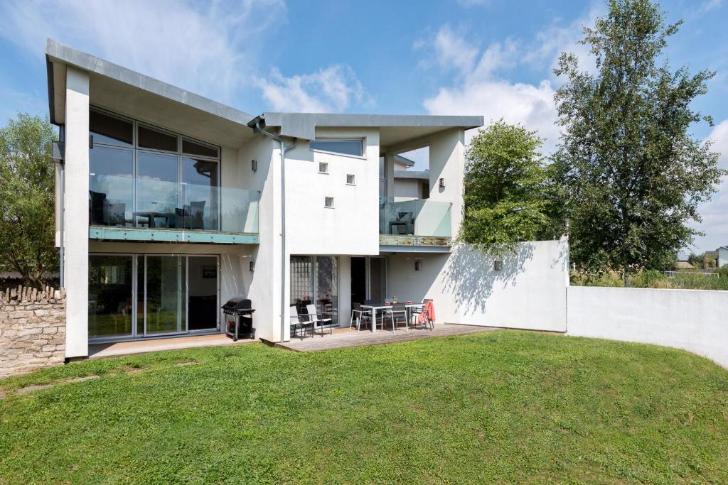 een wit huis met een gazon ervoor bij Lakeside property with spa access on a nature reserve Reid Villa CW01 in Somerford Keynes