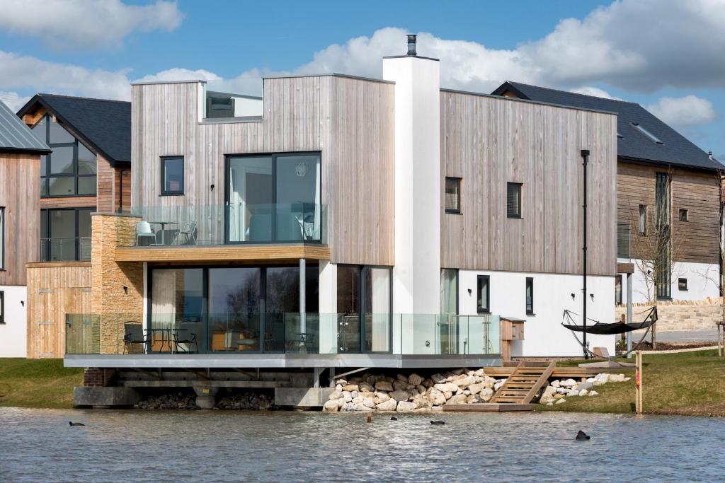 a house on the water with a dock at Lakeside property with spa access on a nature reserve Driftwood BV09 in Warmwell