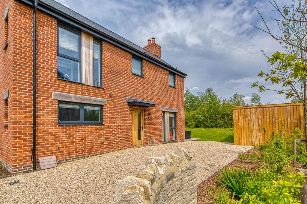 uma casa de tijolos vermelhos com uma porta amarela em Luxury property with access into Spa on a nature reserve Beaumont Village 5 BV05 em Warmwell