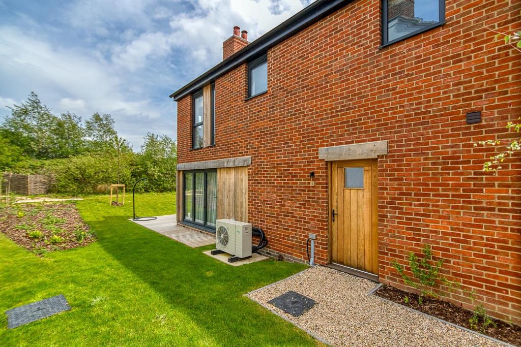 a brick house with a door and a yard at Luxury property with access into Spa on a nature reserve Beaumont Village 5 BV05 in Warmwell