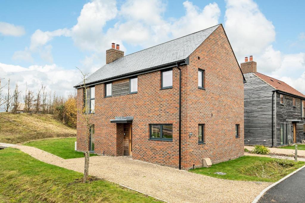 a brick house on a hill with a road at Lakeside property with spa access on a nature reserve Rainbows BV17 in Warmwell