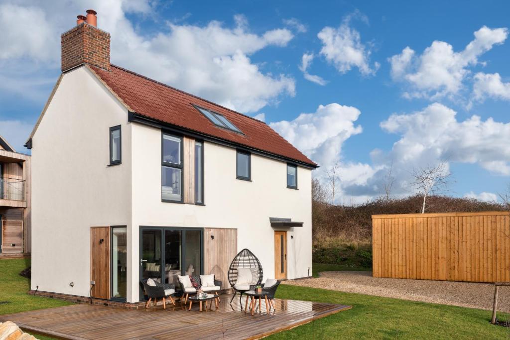 a white house with a deck and chairs at Lakeside property with spa access on a nature reserve Sand Martin BV07 in Warmwell