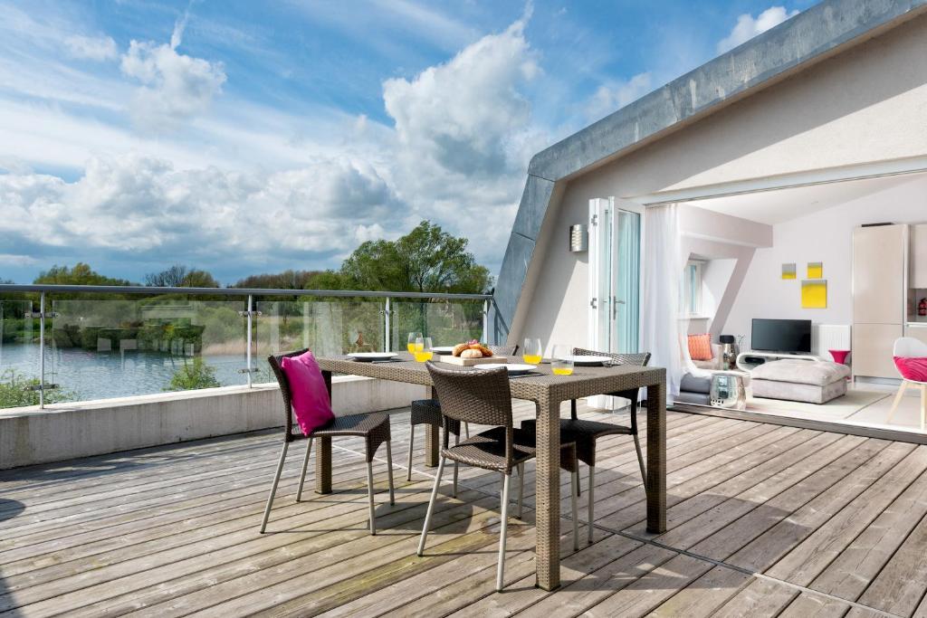 a wooden deck with a table and chairs on a balcony at Penthouse apartment with a Spa on a nature reserve Willow Warbler HM112 in Somerford Keynes