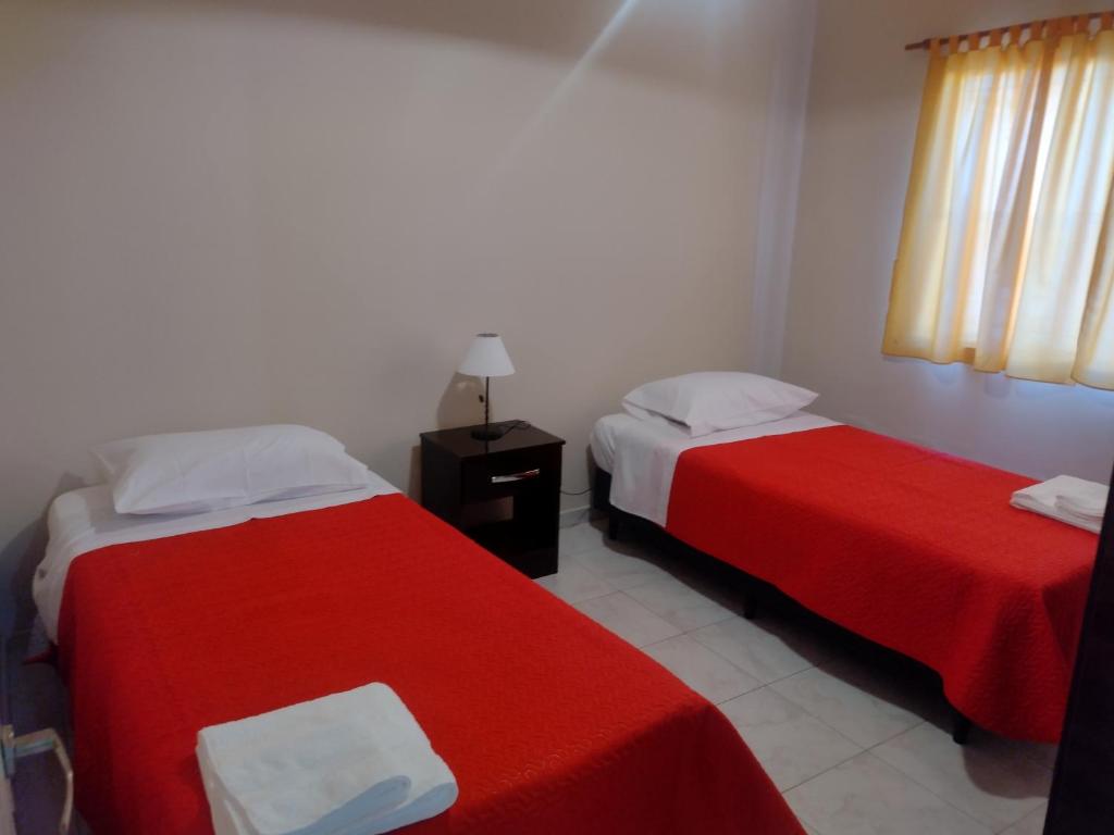 2 camas en una habitación con sábanas rojas y blancas en La Candida en Tunuyán