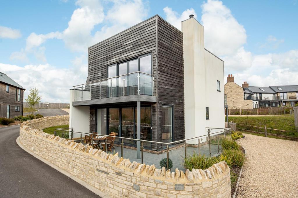 a modern house with a stone wall at Lakeside property with access into Spa on a nature reserve All Decked Out BV28 in Warmwell