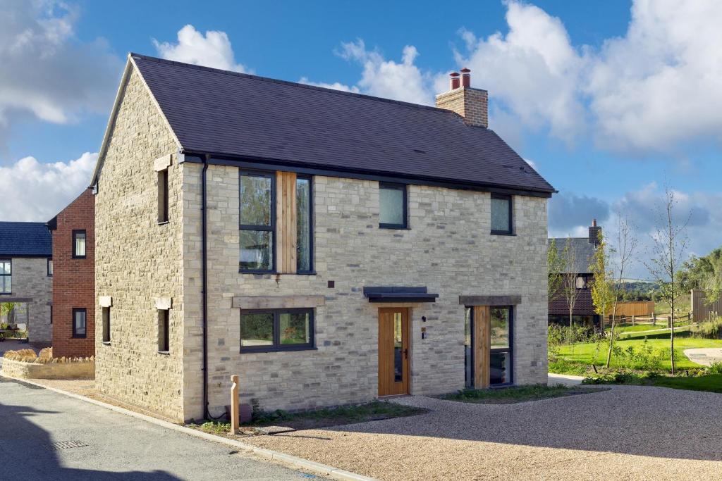 a brick house with a black roof on a street at Lakeside property with spa access on a nature reserve Sunbird Cottage BV20 in Warmwell