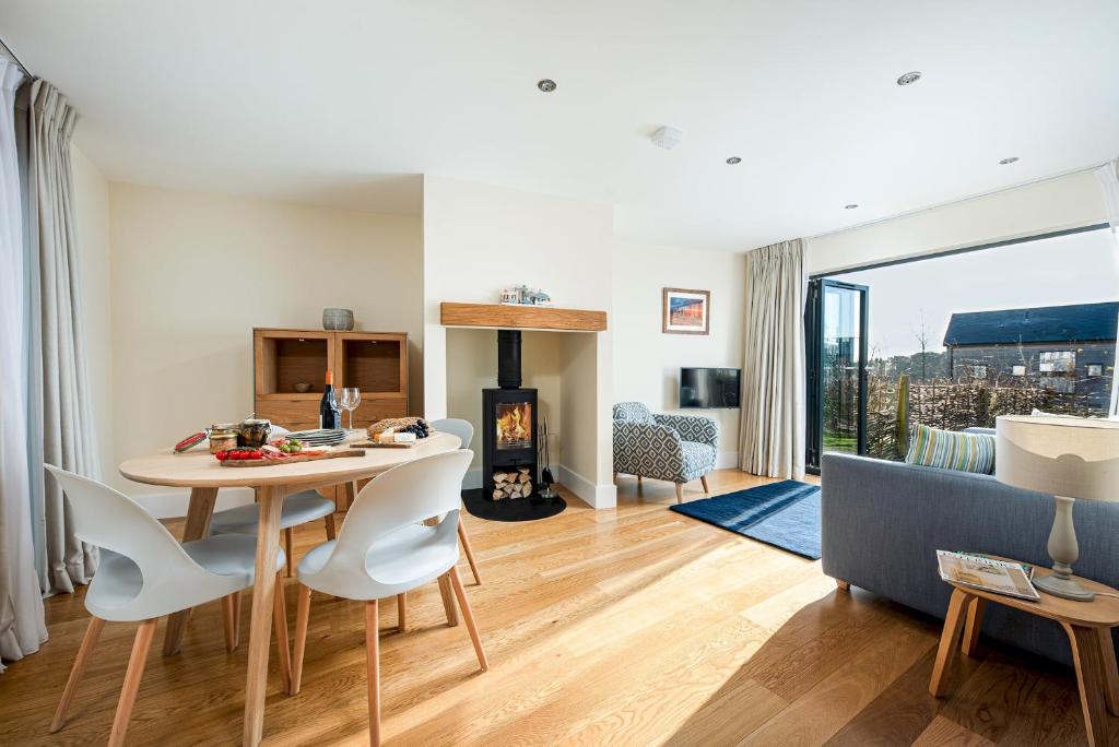 uma sala de estar com uma mesa e cadeiras e uma lareira em Luxury property with spa access on a nature reserve Hambury Cottage BV22 em Warmwell