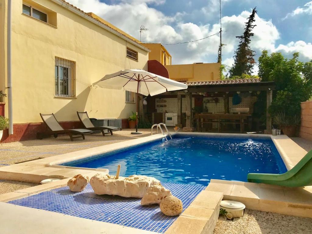 a swimming pool in front of a house with an umbrella at Elegant Villa in Cartagena with Private Pool in Cartagena