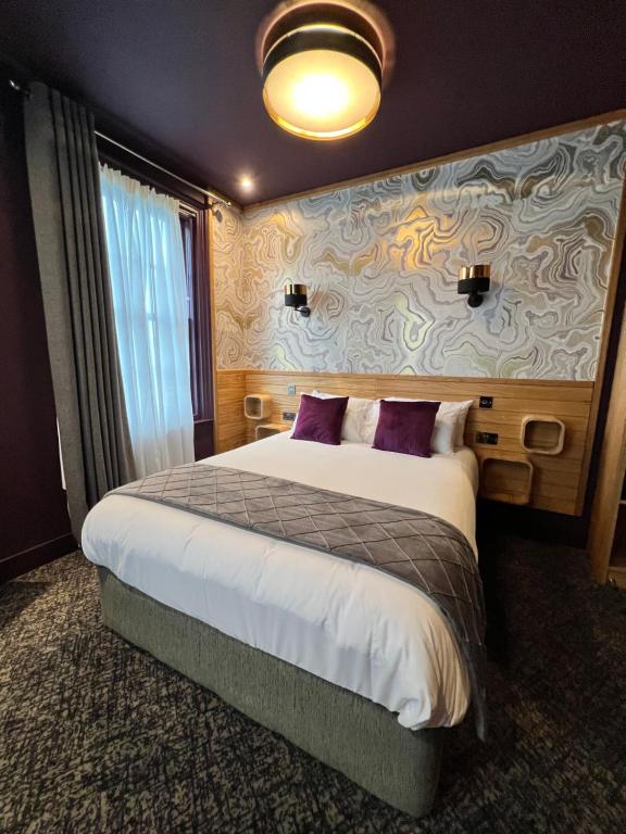 Cette chambre comprend un grand lit avec des oreillers violets. dans l'établissement Lough Rooms at The Artisan, à Strangford