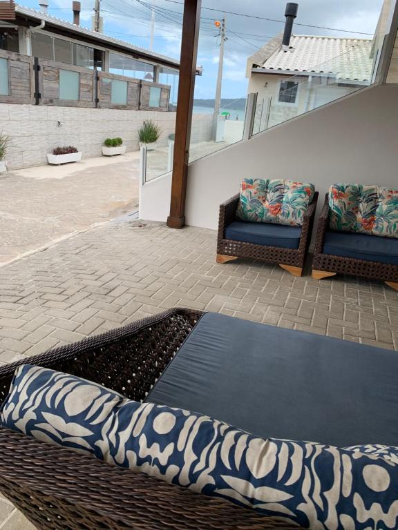 un patio con 2 sillas de mimbre y una mesa en Casa pé na areia Ponta do Papagaio, en Palhoça