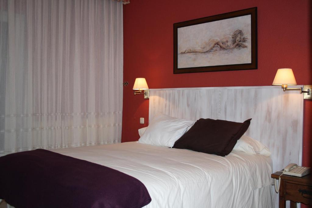 a bedroom with a large white bed with red walls at Hotel Cuatro Calzadas in Martinamor