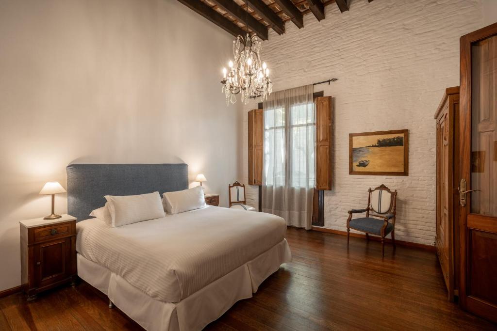 a bedroom with a bed and a chandelier at Posada Manuel Lobo in Colonia del Sacramento