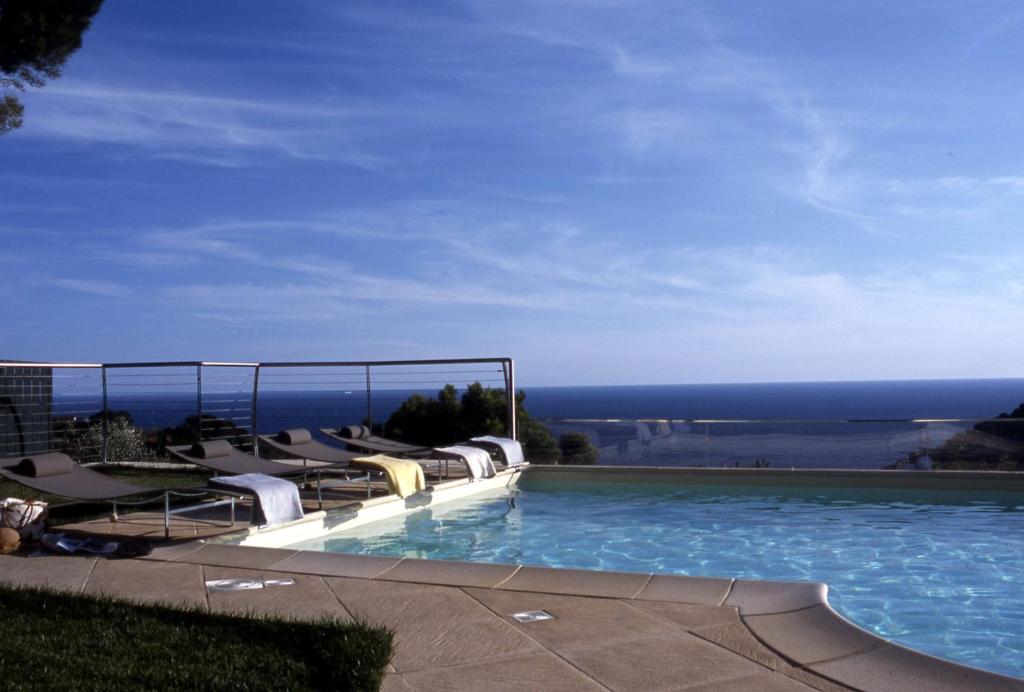 a swimming pool with chairs and a view of the ocean at Agriturismo Uliveto Saglietto in Imperia