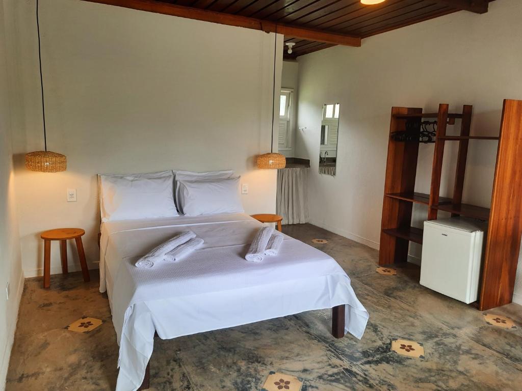 a bedroom with a bed with white sheets and pillows at Pousada Cantoria in Cumuruxatiba