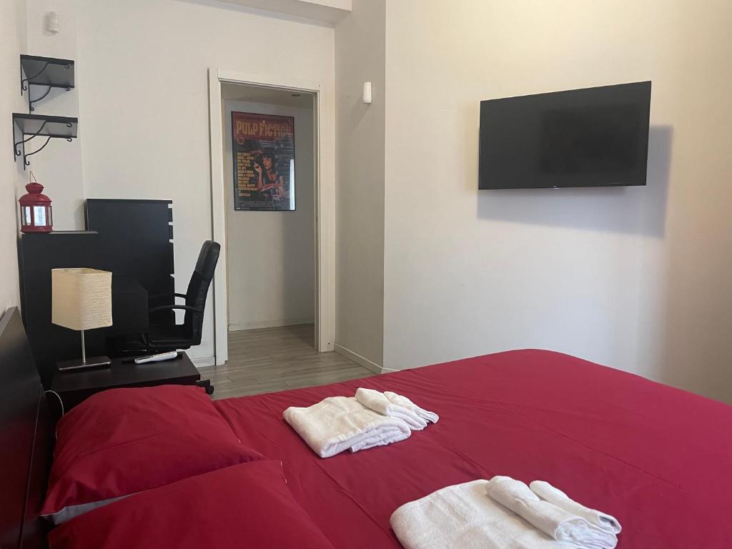 a bedroom with a red bed and a flat screen tv at Gardone Apartment - ampio Appartamento con 2 camere da letto - Comodo per Duomo! in Milan