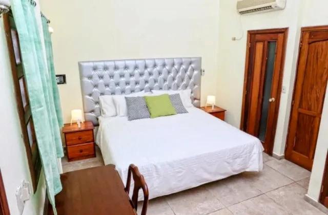 a bedroom with a large white bed and a table at Hotel Aluge in Santo Domingo