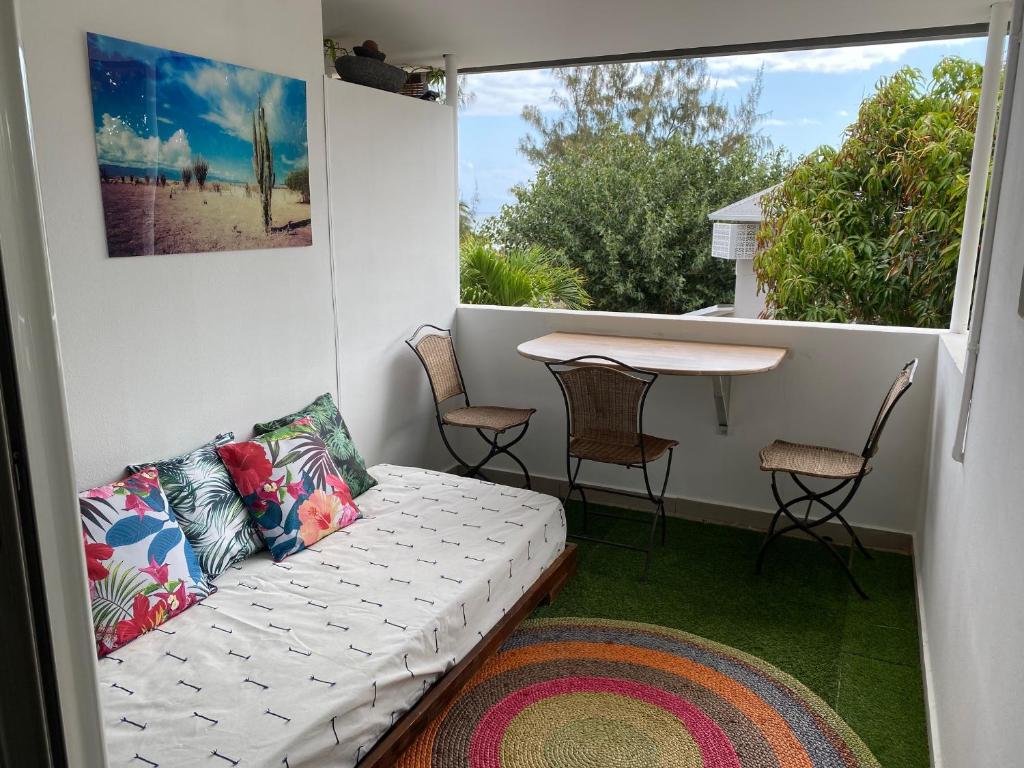 a living room with a couch and a table on a balcony at Appartement OTP2 de standing proche plage et lagon in La Saline les Bains