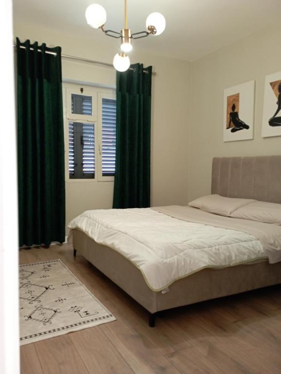 Schlafzimmer mit einem Bett mit grünen Vorhängen und einem Kronleuchter in der Unterkunft Piazza_Apartments_Tirana in Tirana