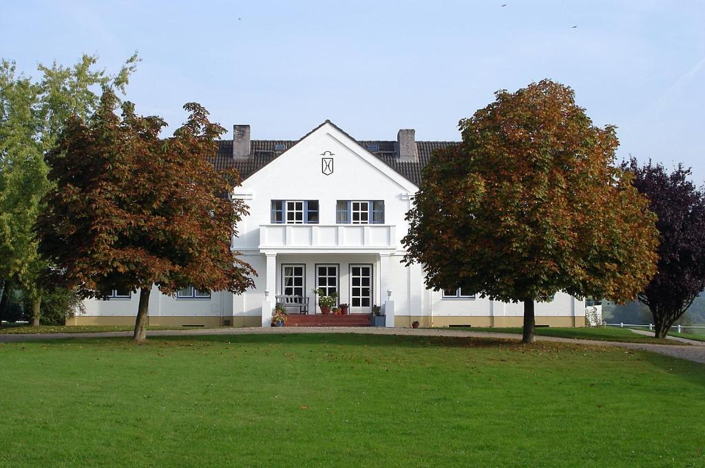 ein weißes Haus mit zwei Bäumen davor in der Unterkunft Moorberghof in Sagau