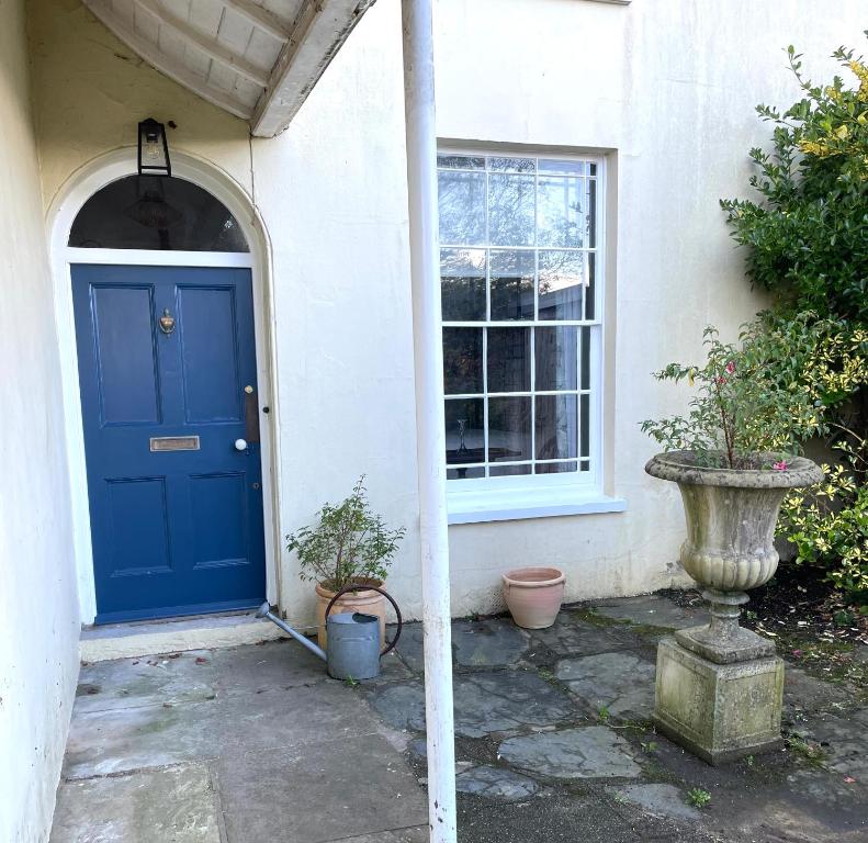 Luxury flat in Totnes في توتنس: الباب الأزرق للمنزل الذي يحتوي على اثنين من النباتات الفخارية