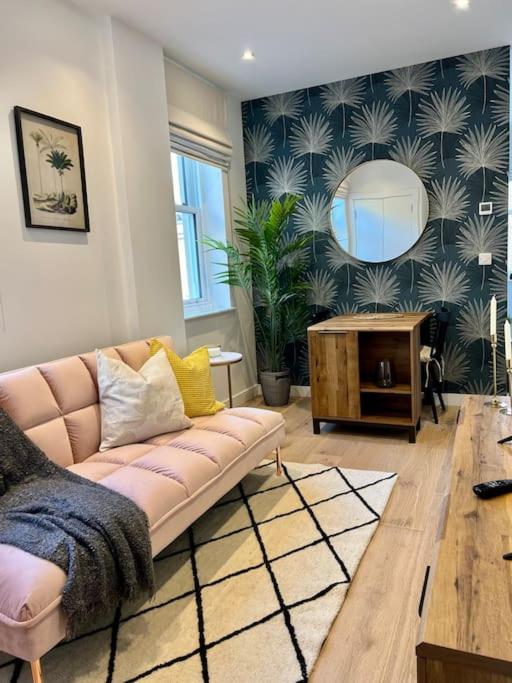 a living room with a pink couch and a mirror at Cosy, modern 1-bed apartment in Bath's iconic centre in Bath