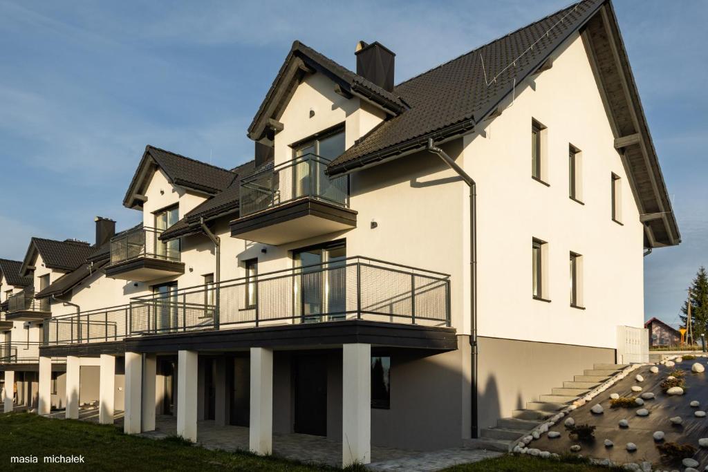 duży biały budynek z czarnym dachem w obiekcie DAJ SOBIE CZAS Apartament w Istebnej