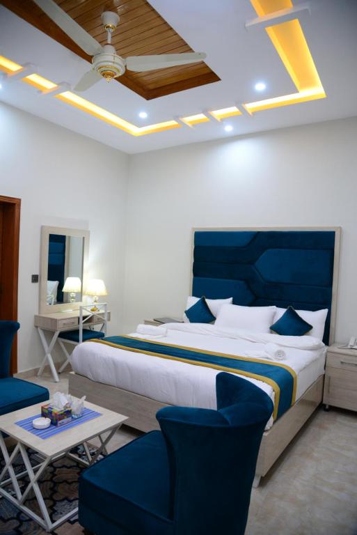 1 dormitorio con 1 cama grande, mesa y sillas en Hotel Grand Lahore, en Lahore
