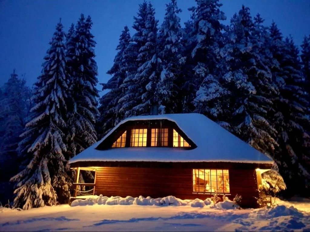 una cabaña en la nieve por la noche en Murmuļmuiža, en Zāģeri