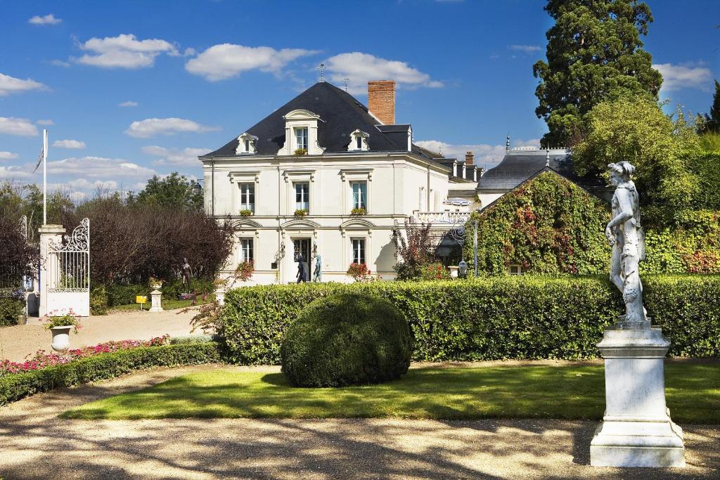 a white house with a statue in front of it at Hôtel Le Choiseul in Amboise