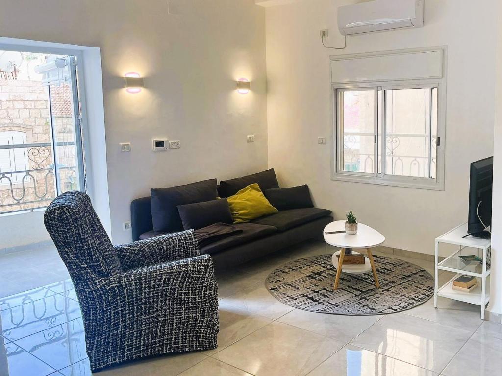ein Wohnzimmer mit einem Sofa, Stühlen und einem Tisch in der Unterkunft A cozy 2bdrm home in Wadi-Nisnas Haifa in Haifa