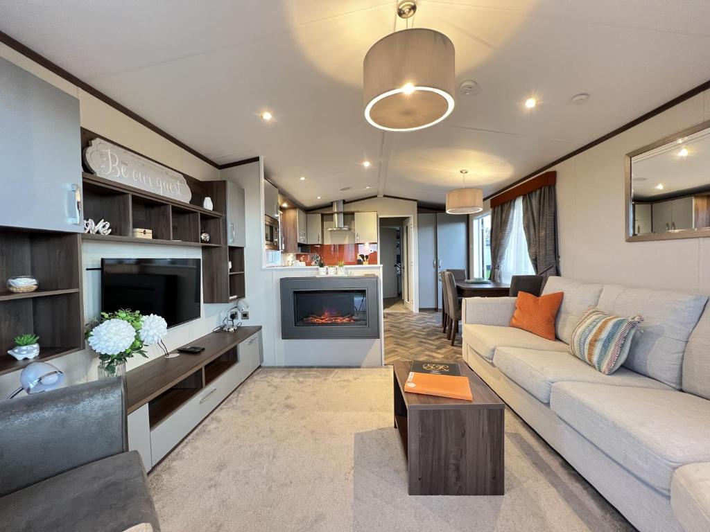 a living room with a couch and a tv at The Coorie Neuk Hot Tub Lodge 34 Cameron, St Andrews in St. Andrews