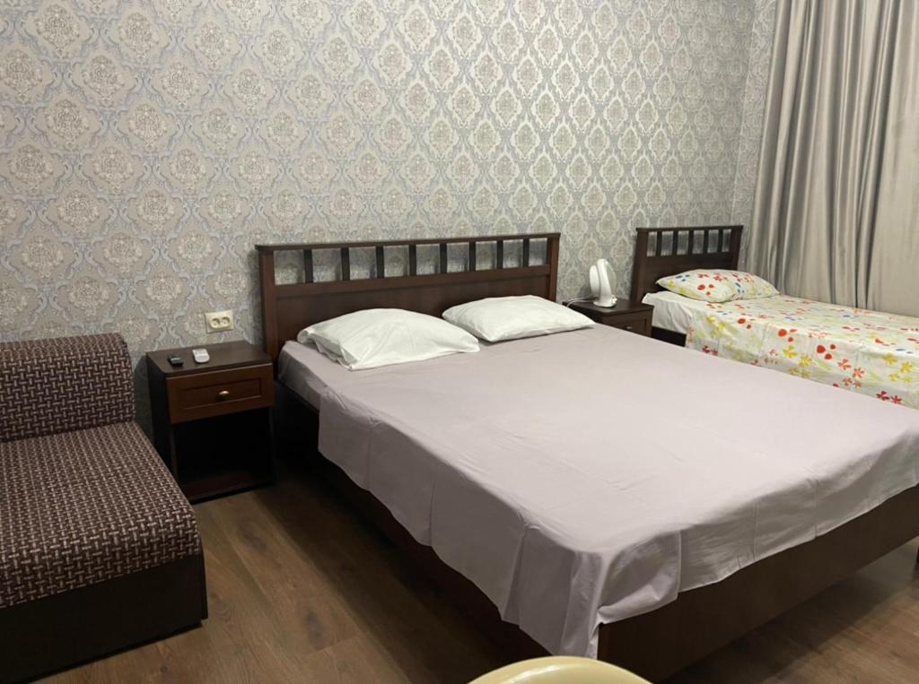 a bedroom with two beds and a chair at Emili in Pizunda